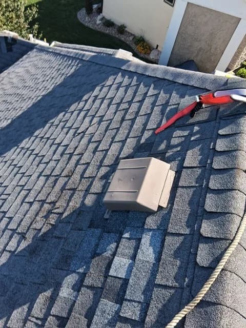 New box roof vent installed on a shingle roof with fresh shingles around it and a red tool in the background