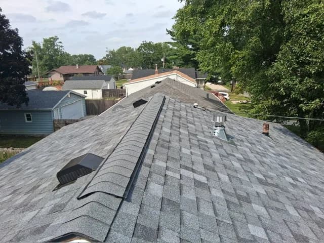 Aerial view of a completed hip roof with new architectural shingles, full house and yard visible, Des Moines