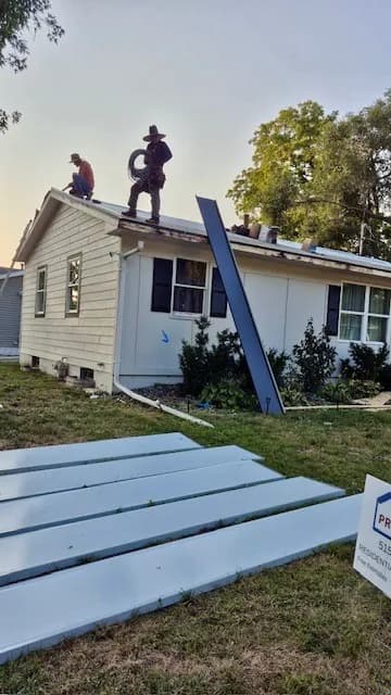 Crew tearing off and reroofing a ranch home, tarps staged over the landscaping