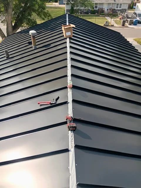 Finished dark standing seam metal roof running straight to the ridge